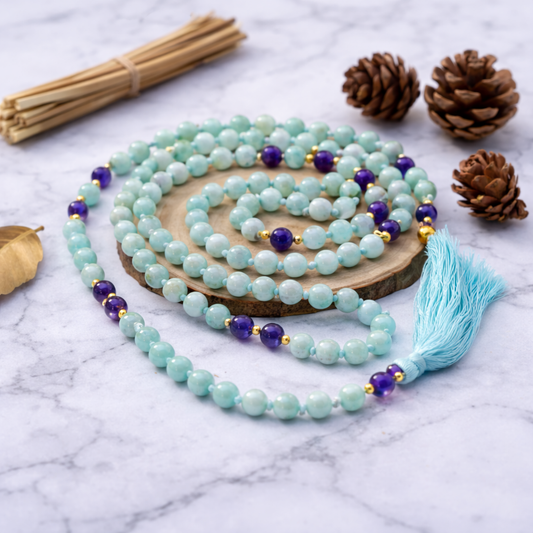Turquoise beaded Amazonite and Amethyst prayer malas with purple accents on a marble surface with pine cones and sticks.