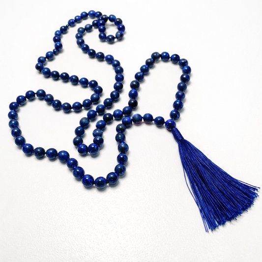 Blue lapis lazuli beaded Mala necklace with a tassel on a white background