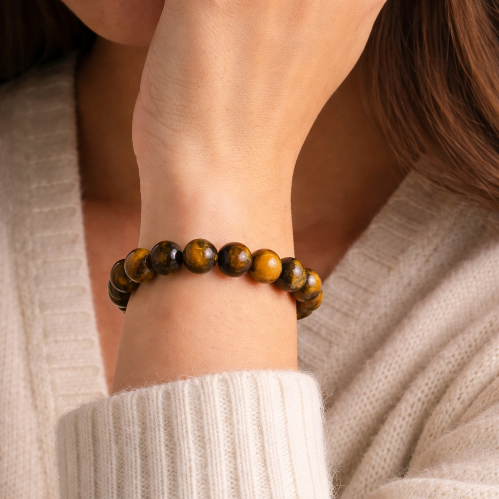 Close-up of a person wearing a tiger eye bracelet on a neutral background